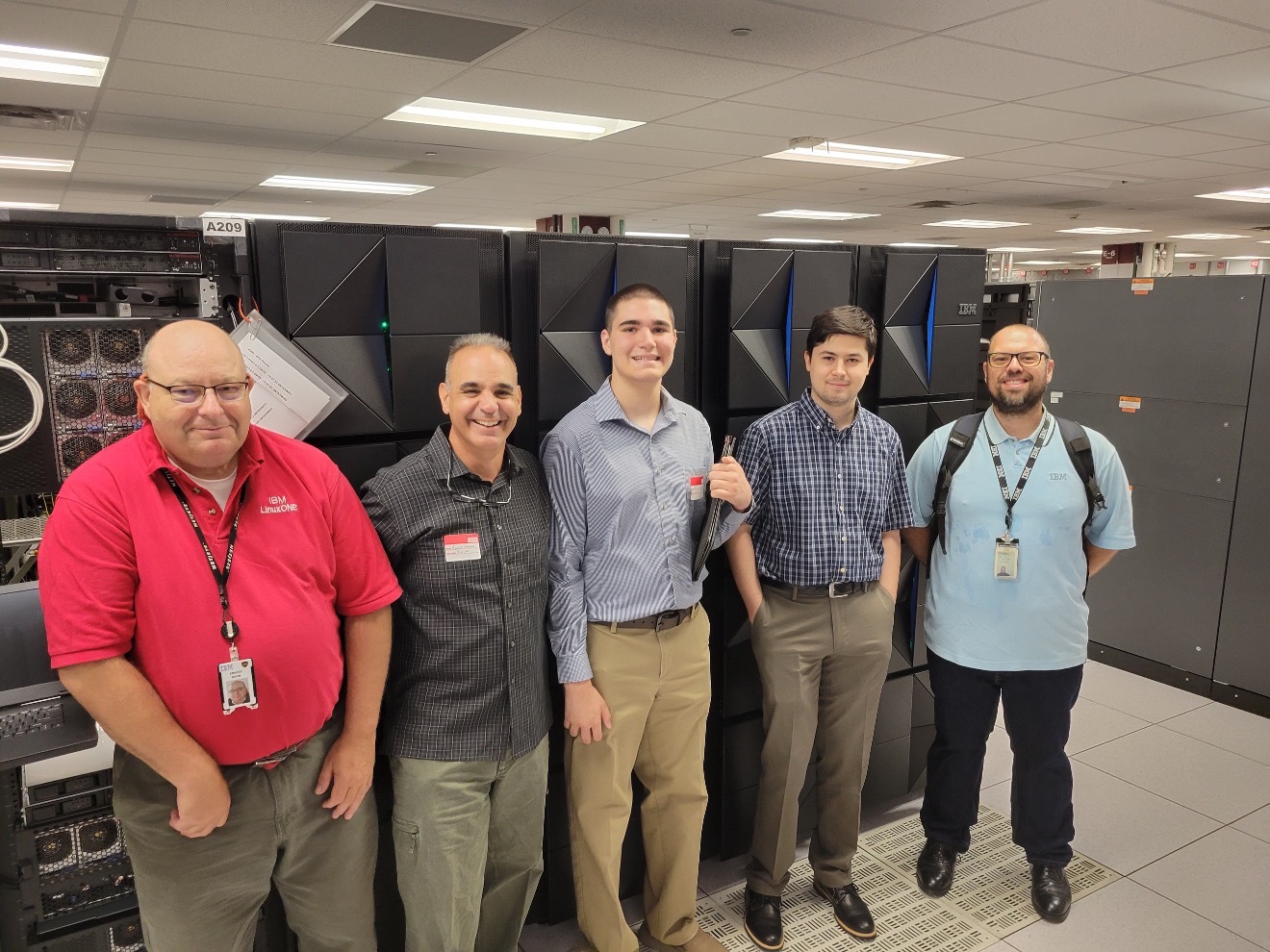 L to R: Paul Novak, Connor Kurkosky, Enzo Damato, Vinny Damato and Ernest Horn. The group stands in front of several mainframe machines..